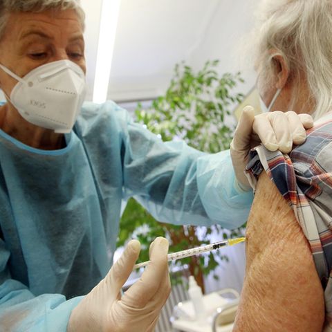 Ein älterer Mann wird von einer Krankenschwester gegen Covid-19 geimpft