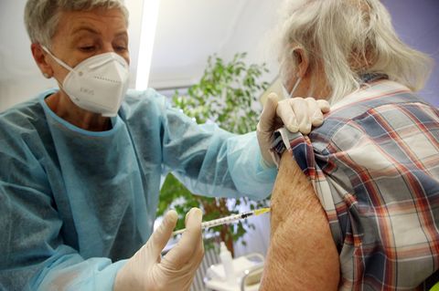 Ein älterer Mann wird von einer Krankenschwester gegen Covid-19 geimpft