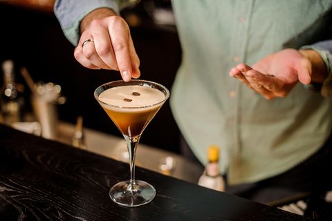 Espresso Martini: Ein Barkeeper garniert den vollendeten Espresso Martini mit drei Kaffeebohnen.