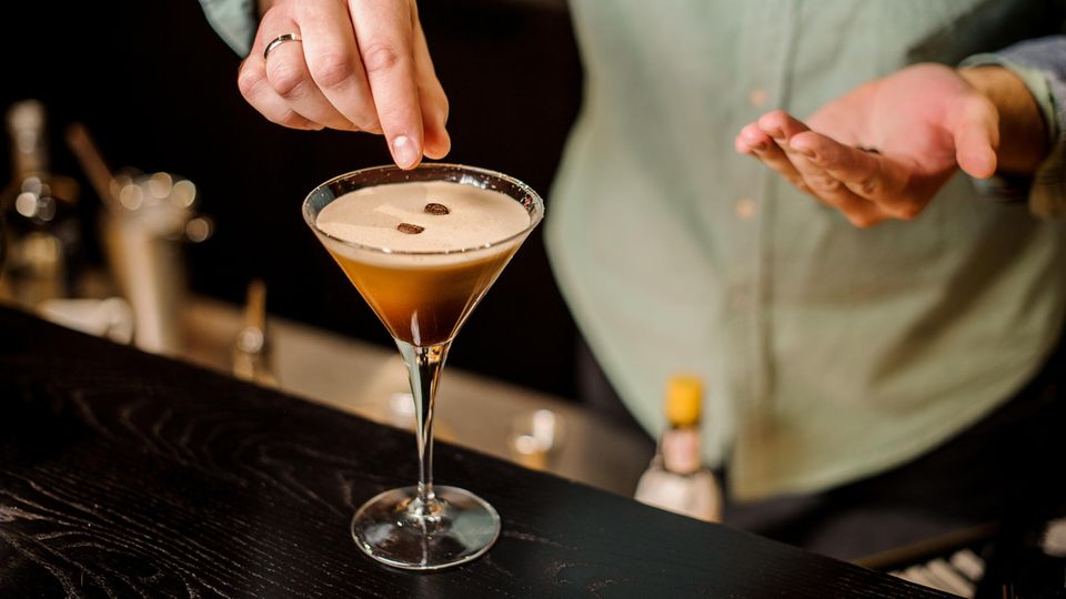 Espresso Martini: Ein Barkeeper garniert den vollendeten Espresso Martini mit drei Kaffeebohnen.