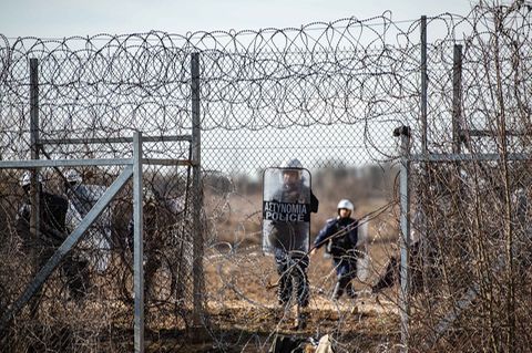Ein griechischer Polizist steht an einem Loch im Zaun an der griechisch-türkischen Grenze