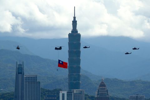 Ein Militärhubschrauber zieht eine riesige Taiwan-Fahne hinter sich her und fliegt vor "Taipei 101" vorbei