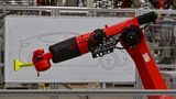 Ein Roboter zeichnet einen Tesla Model Y zum Tag der offenen Tür in einer Produktionshalle der Tesla Gigafactory. Die Werkhallen sind voll mit Hightech, ein Teil der Produktion wird von Maschinen übernomme