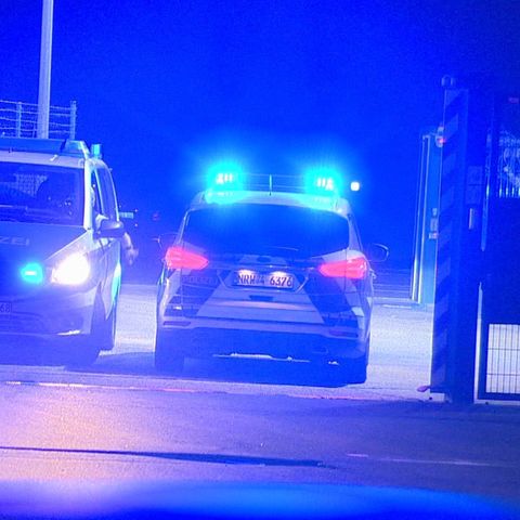 Polizisten passieren in Polizeifahrzeugen ein Tor am Flughafen Weeze