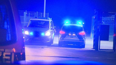 Polizisten passieren in Polizeifahrzeugen ein Tor am Flughafen Weeze