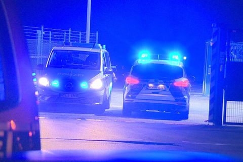 Polizisten passieren in Polizeifahrzeugen ein Tor am Flughafen Weeze