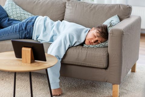 Ein Mann liegt auf einer Couch und schaut auf ein Tablet