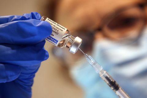 Eine Spritze wird von einer Person mit medizinischen Handschuhen aufgezogen