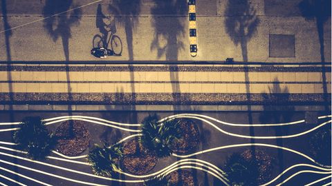 Drohnenfoto eines Fahrradfahrers der durch den Superkilen Park, ein mit weißen Linien gestalteter Platz, fährt.