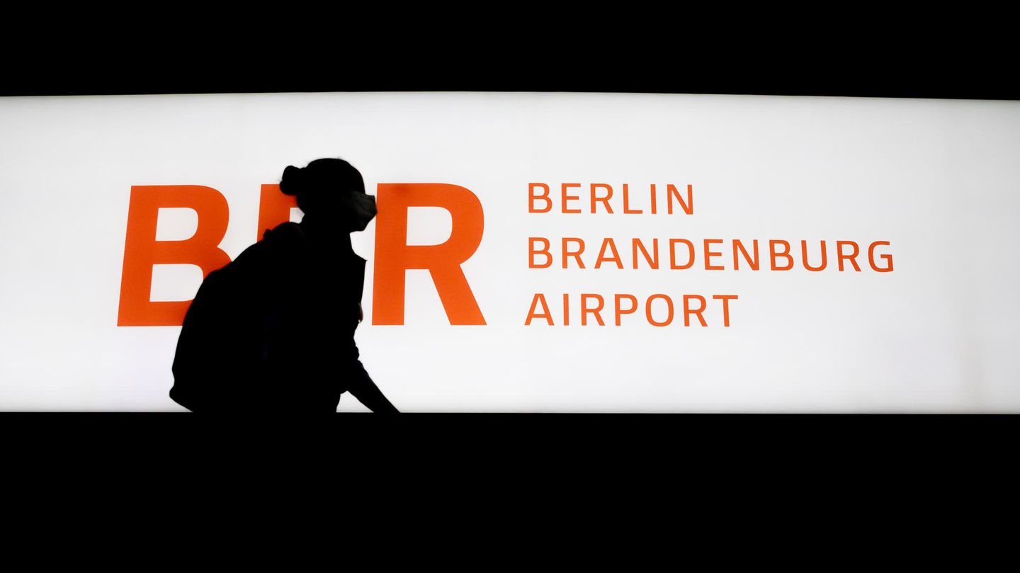 Passagierin läuft an einem beleucteten Schild BER Berlin Brandenburg Airport vorbei