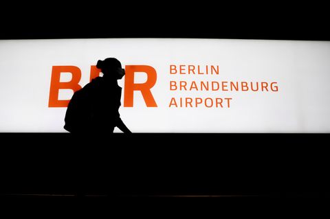 Passagierin läuft an einem beleucteten Schild BER Berlin Brandenburg Airport vorbei