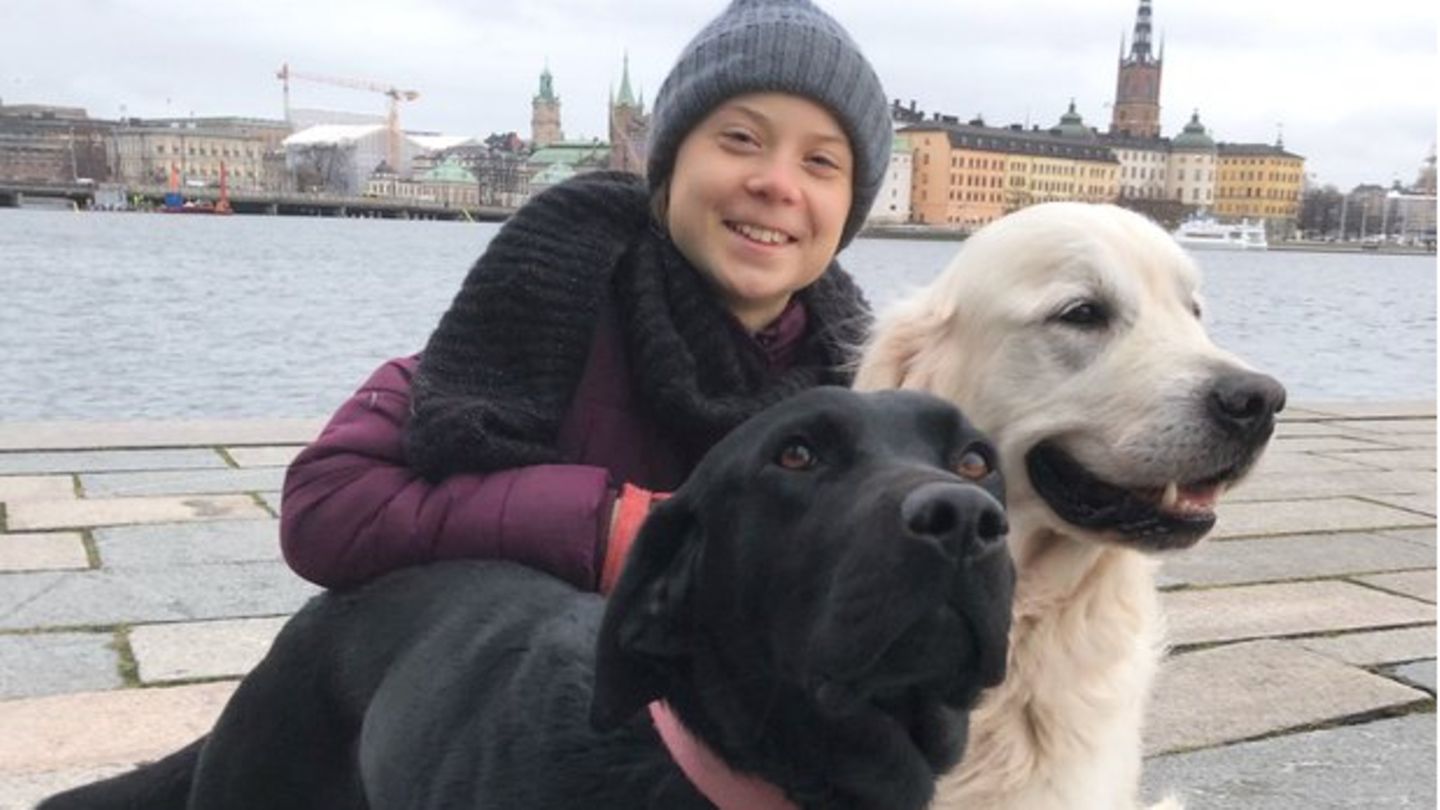 Greta Thunberg kniet neben ihren Hunden Moses und Roxy