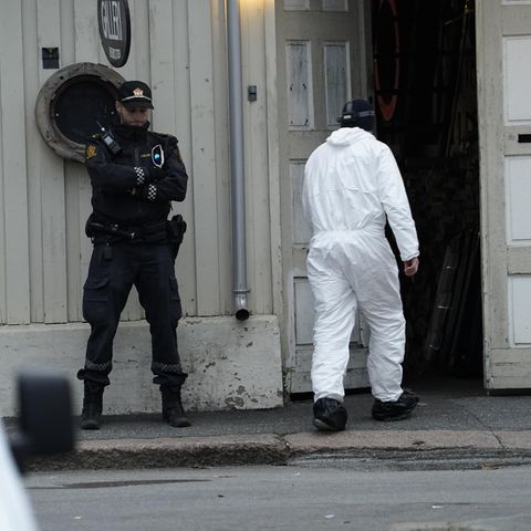 Techniker der Polizei geht nach einer Gewalttat mit fünf Toten und zwei Verletzten in ein Gebäude, vor dem ein Polizist Wache steht