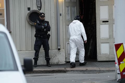 Techniker der Polizei geht nach einer Gewalttat mit fünf Toten und zwei Verletzten in ein Gebäude, vor dem ein Polizist Wache steht