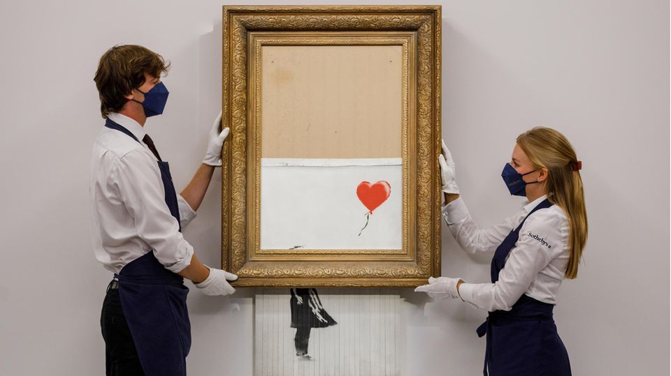 Mitarbeiter von Sotheby's zeigen das geschredderte Werk Girl with Balloon von Banksy Mitarbeiter von Sotheby's zeigen das geschredderte Werk Girl with Balloon von Banksy