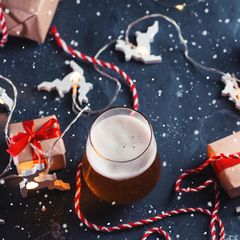 Bier-Adventskalender: Ein frisch gezapftes Bier steht zwischen Geschenken.