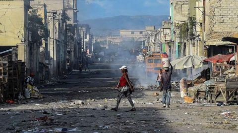 Mehrere Menschen laufen über eine Straße in der Downtown von Haitis Hauptstadt Port-au-Prince