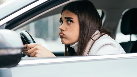 Eine Frau sitzt mit angespanntem Gesichtsausdruck in einem Auto