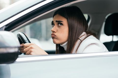 Eine Frau sitzt mit angespanntem Gesichtsausdruck in einem Auto