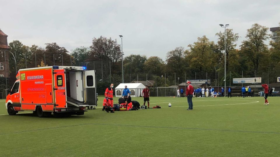 Krankenwagen auf Fußballfeld während Rettungshelfer Berkant Aydin behandeln