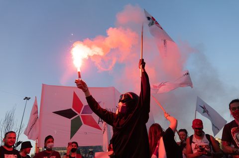 Demonstrant protestiert mit Flagge und Bengalo