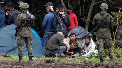 Polnische Sicherheitskräfte umringen Migranten, die an der Grenze zu Weißrussland festsitzen