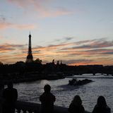 Touristen stehen in Paris auf einer Brücke über die Seine und fotografieren den Eiffelturm bei Sonnenuntergang