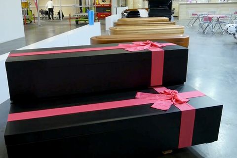 Zwei schwarze Särge mit roten Schleifen werden auf einer Bestattungsmesse ausgestellt.