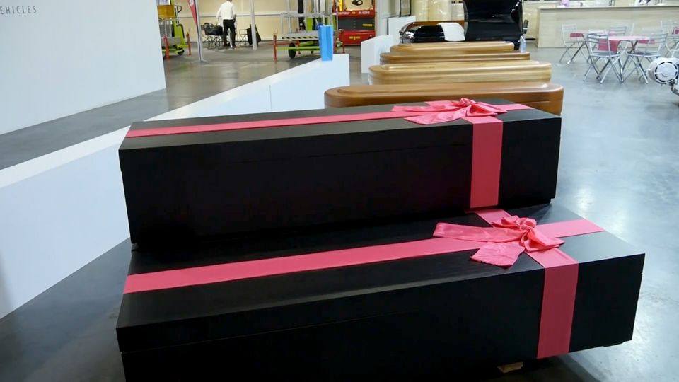 Zwei schwarze Särge mit roten Schleifen werden auf einer Bestattungsmesse ausgestellt.