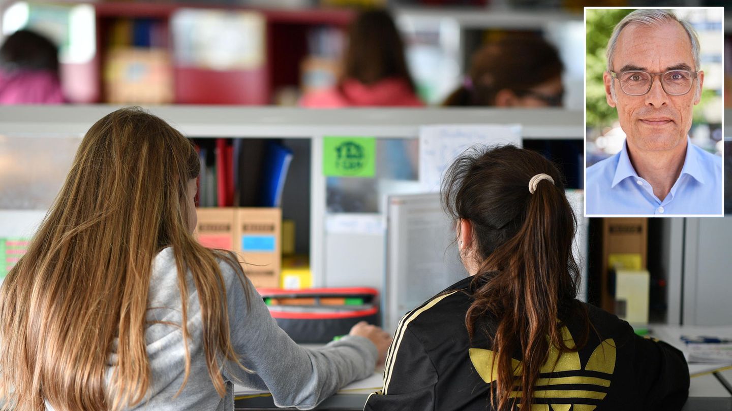 Von hinten sind zwei Schülerinnen mit langen Haaren zu sehen, die gemeinsam in einem Klassenraum sitzen