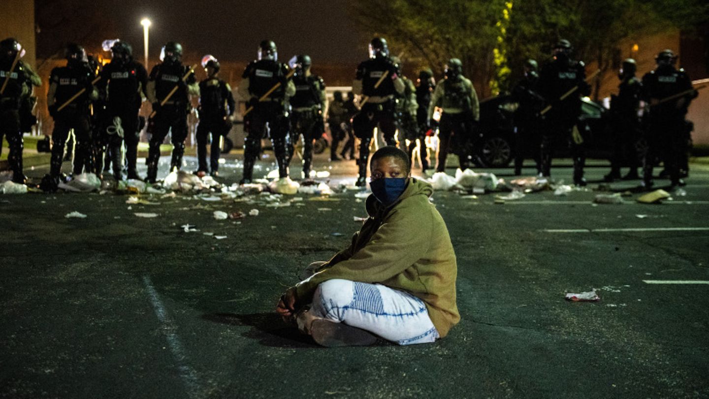 Ein Demonstrant sitzt vor einer Reihe Bereitschaftspolizisten in der Kleinstadt Brooklyn Center am Nordrand von Minneapolis