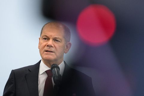 Olaf Scholz am Mikrofon neben einem roten Licht