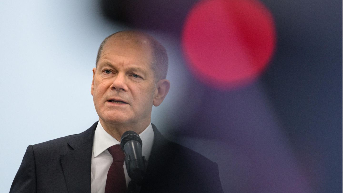 Olaf Scholz am Mikrofon neben einem roten Licht