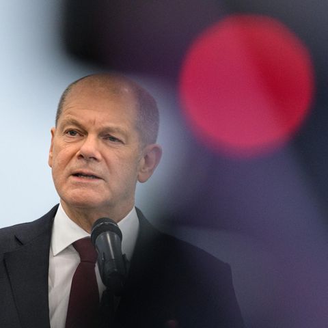 Olaf Scholz am Mikrofon neben einem roten Licht