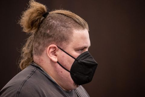 Ein übergewichtiger weißer Mann mit an den Seiten rasierten und oben langen dunkelblonden Haaren