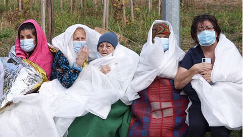 Frauen tragen Mund-Nasen-Schutz und sind in Decken und Laken gewickelt