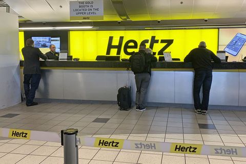 Menschen werden an einem Schalter des Autovermieters Hertz bedient.