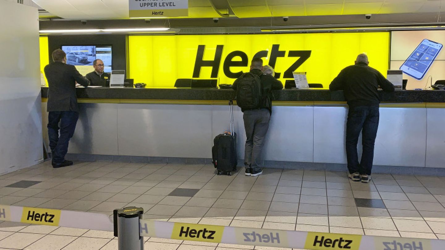 Menschen werden an einem Schalter des Autovermieters Hertz bedient.