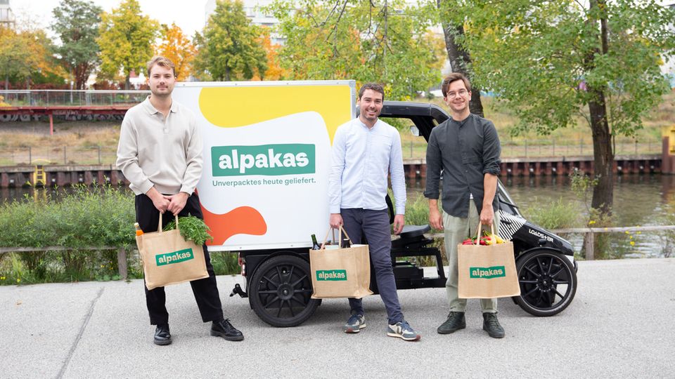 The alpacas founders stand in front of an electric cargo bike