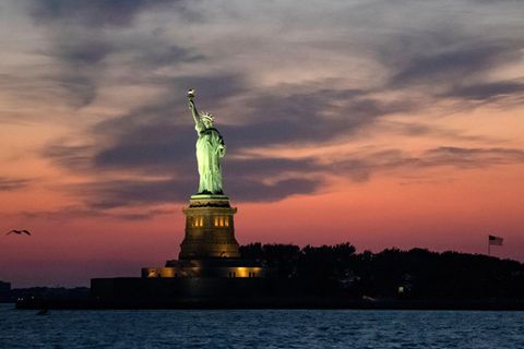 USA, New York: Die Freiheitsstatue wird bei Abenddämmerung angestrahlt