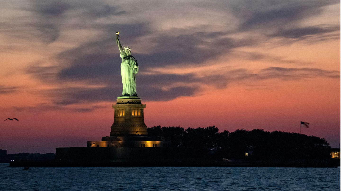 USA-Reisen ab November möglich – nach Impfung mit diesen anerkannten Stoffen USA, New York: Die Freiheitsstatue wird bei Abenddämmerung angestrahlt