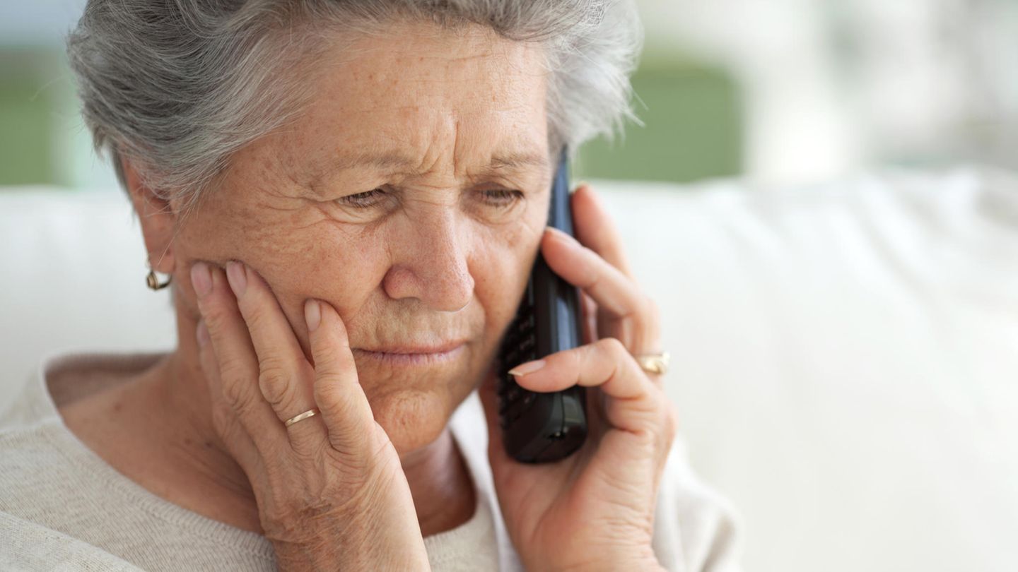 Eine Seniorin hat den Hörer ans Ohr gelegt