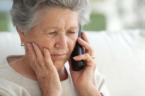 Eine Seniorin hat den Hörer ans Ohr gelegt