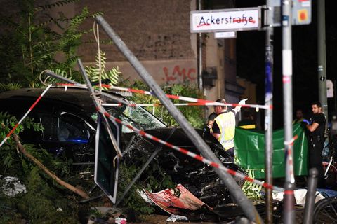 An einem zerstörten Auto halten Polizisten ein Plane