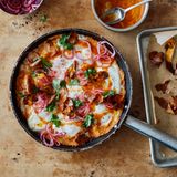 Süßkartoffel-Shakshuka mit Srirachabutter und gepickelten Zwiebeln      Zutaten:   1 kg Süßkartoffeln, sauber abgeschrubbt,1 kleine rote Zwiebel, in feine Ringe geschnitten (100 g), 2 EL Zitronensaft, 3 EL Olivenöl, 150 g gereifter Cheddar, grob gerieben, 3 Knoblauchzehen, zerdrückt, 1 TL Kreuzkümmelsamen, im Mörser grob zerstoßen, 8 Eier, 25 g Butter, ¾ EL Sriracha-Chilisauce, 2 EL Korianderblätter, Salz und schwarzer Pfeffer      Zubereitung:  1. Den Backofen auf 200 °C (Umluft) vorheizen. Die Süßkartoffeln rundherum acht- bis zehnmal mit einer Gabel einstechen, dann auf ein mit Backpapier ausgelegtes Blech geben. Im Ofen 45–50 Minuten backen, bis sie weich und durchgegart sind. Die Süßkartoffeln zum Abkühlen beiseitestellen, die Backofentemperatur auf 180 °C (Umluft) reduzieren.  2. Die Zwiebelringe in einer kleinen Schüssel mit 1 EL Zitronensaft sowie 1 Prise Salz verrühren; beiseitestellen.  3. Von den gegarten Süßkartoffeln die Schale abziehen. Das Fleisch in etwa 4 cm große Stücke zupfen und in einer großen Schüssel beiseitestellen. Die Kartoffelschalen zurück auf das Backblech geben und mit 1 EL Öl, ¼ TL Salz sowie 1 kräftigen Prise Pfeffer vermengen. Im Ofen 8 Minuten backen, bis sie schön gebräunt und knusprig sind. Zum Abkühlen beiseitestellen.  4. Das Süßkartoffelfleisch mit einer Gabel fein zerdrücken. Den Cheddar, den Knoblauch, den Kreuzkümmel, 1 EL Öl, den restlichen EL Zitronensaft, 1 TL Salz sowie 1 kräftige Prise Pfeffer untermengen.  5. In einer großen Pfanne, für die ein Deckel vorhanden ist, den restlichen EL Öl verteilen. Die Süßkartoffelmasse hineingeben und mit einem Löffel gleichmäßig verteilen. Bei mittlerer bis starker Hitze etwa 7 Minuten braten, bis die Unterseite etwas Farbe angenommen hat. Die Hitze auf mittlere Stufe reduzieren und mit einem Löffel acht Vertiefungen in die Süßkartoffelmasse drücken. In jede Vertiefung ein Ei aufschlagen, salzen und pfeffern. In der zugedeckten Pfanne 4–5 Minuten garen, bis das Eiweiß fest ist, die Eigelbe aber noch flüssig.  6. Während die Eier garen, Butter und Sriracha-Sauce in einem kleinen Topf bei mittlerer Temperatur erhitzen, bis die Butter geschmolzen ist, dabei unablässig mit einem Schneebesen schlagen, bis die Mischung emulgiert ist. Die Sriracha-Butter vom Herd nehmen, bevor sie Blasen wirft – sie darf nicht gerinnen.  7. Die Sriracha-Butter über die Eier gießen, 1 Handvoll von den knusprigen Schalenstücken, die Hälfte der gepickelten Zwiebelringe sowie die Korianderblätter hinzufügen. Sofort servieren und die Reste von knuspriger Kartoffelschale und eingelegter Zwiebel separat reichen.