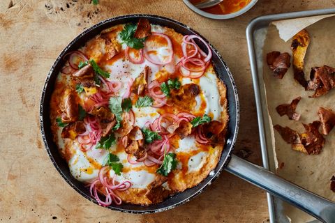 Süßkartoffel-Shakshuka mit Srirachabutter und gepickelten Zwiebeln      Zutaten:   1 kg Süßkartoffeln, sauber abgeschrubbt,1 kleine rote Zwiebel, in feine Ringe geschnitten (100 g), 2 EL Zitronensaft, 3 EL Olivenöl, 150 g gereifter Cheddar, grob gerieben, 3 Knoblauchzehen, zerdrückt, 1 TL Kreuzkümmelsamen, im Mörser grob zerstoßen, 8 Eier, 25 g Butter, ¾ EL Sriracha-Chilisauce, 2 EL Korianderblätter, Salz und schwarzer Pfeffer      Zubereitung:  1. Den Backofen auf 200 °C (Umluft) vorheizen. Die Süßkartoffeln rundherum acht- bis zehnmal mit einer Gabel einstechen, dann auf ein mit Backpapier ausgelegtes Blech geben. Im Ofen 45–50 Minuten backen, bis sie weich und durchgegart sind. Die Süßkartoffeln zum Abkühlen beiseitestellen, die Backofentemperatur auf 180 °C (Umluft) reduzieren.  2. Die Zwiebelringe in einer kleinen Schüssel mit 1 EL Zitronensaft sowie 1 Prise Salz verrühren; beiseitestellen.  3. Von den gegarten Süßkartoffeln die Schale abziehen. Das Fleisch in etwa 4 cm große Stücke zupfen und in einer großen Schüssel beiseitestellen. Die Kartoffelschalen zurück auf das Backblech geben und mit 1 EL Öl, ¼ TL Salz sowie 1 kräftigen Prise Pfeffer vermengen. Im Ofen 8 Minuten backen, bis sie schön gebräunt und knusprig sind. Zum Abkühlen beiseitestellen.  4. Das Süßkartoffelfleisch mit einer Gabel fein zerdrücken. Den Cheddar, den Knoblauch, den Kreuzkümmel, 1 EL Öl, den restlichen EL Zitronensaft, 1 TL Salz sowie 1 kräftige Prise Pfeffer untermengen.  5. In einer großen Pfanne, für die ein Deckel vorhanden ist, den restlichen EL Öl verteilen. Die Süßkartoffelmasse hineingeben und mit einem Löffel gleichmäßig verteilen. Bei mittlerer bis starker Hitze etwa 7 Minuten braten, bis die Unterseite etwas Farbe angenommen hat. Die Hitze auf mittlere Stufe reduzieren und mit einem Löffel acht Vertiefungen in die Süßkartoffelmasse drücken. In jede Vertiefung ein Ei aufschlagen, salzen und pfeffern. In der zugedeckten Pfanne 4–5 Minuten garen, bis das Eiweiß fest ist, die Eigelbe aber noch flüssig.  6. Während die Eier garen, Butter und Sriracha-Sauce in einem kleinen Topf bei mittlerer Temperatur erhitzen, bis die Butter geschmolzen ist, dabei unablässig mit einem Schneebesen schlagen, bis die Mischung emulgiert ist. Die Sriracha-Butter vom Herd nehmen, bevor sie Blasen wirft – sie darf nicht gerinnen.  7. Die Sriracha-Butter über die Eier gießen, 1 Handvoll von den knusprigen Schalenstücken, die Hälfte der gepickelten Zwiebelringe sowie die Korianderblätter hinzufügen. Sofort servieren und die Reste von knuspriger Kartoffelschale und eingelegter Zwiebel separat reichen.
