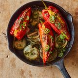 Paprikaschoten mit Maisfüllung und gepickelten Jalapeños      Zutaten:  1 grüne Jalapeño-Chilischote, in feine Ringe geschnitten (15 g), 2 EL Apfelessig, 1 TL Zucker, 250 g TK-Maiskörner, aufgetaut, 100 g Schlagsahne, 50 g Instant-Polenta, 3 Knoblauchzehen, zerdrückt, 1 Ei, 105 ml Olivenöl, 75 g schnittfester Mozzarella, grob gerieben, 75 g gereifter Cheddar, grob gerieben, 4 rote Spitzpaprikaschoten, 2 Zwiebeln, jeweils in 5 Scheiben à 1 cm geschnitten, 5 g Thymianzweige, 10 g Koriandergrün, fein gehackt, Salz und schwarzer Pfeffer      Zubereitung:  1. Den Backofen auf 180 °C (Umluft) vorheizen.  2. Die Chiliringe in einer kleinen Schüssel mit Essig und Zucker verrühren. Beiseitestellen.  3. Den Mais mit Sahne, Polenta, zwei Dritteln des Knoblauchs, dem Ei, 1 EL Öl, ¾ TL Salz und 1 sehr kräftigen Prise Pfeffer im Mixer in wenigen kurzen Intervallen sehr grob pürieren. In eine Schüssel geben und beide Käsesorten unterrühren.  4. Die Paprikaschoten mit einem kleinen scharfen Messer längs einschneiden, ohne die Enden zu durchtrennen; die Stiele intakt lassen. Mit den Fingern die Kerne vorsichtig entfernen. Die Schoten mit der Maismischung füllen.  5. In einer großen gusseisernen Pfanne 1 EL Öl verteilen und mit Zwiebelscheiben und Thymian bedecken; leicht salzen und pfeffern. Die Paprikaschoten mit der Öffnung nach oben auf die Zwiebeln setzen und mit 1 EL Öl beträufeln. Mit etwas Salz und Pfeffer bestreuen, dann 200 ml Wasser in die Pfanne (nicht auf die Paprikaschoten) gießen. 30 Minuten backen, dann die Ofentemperatur auf 200 °C (Umluft) erhöhen und die Schoten weitere 20 Minuten backen, bis alles weich und schön gebräunt ist.  6. Inzwischen die restlichen 4 EL Öl in einer kleinen Schüssel mit Koriandergrün, 1 Msp. Salz und etwas Pfeffer verrühren.  7. Die Paprikaschoten mit dem Koriander-Öl beträufeln, mit den gepickelten Jalapeños bestreuen und warm servieren.