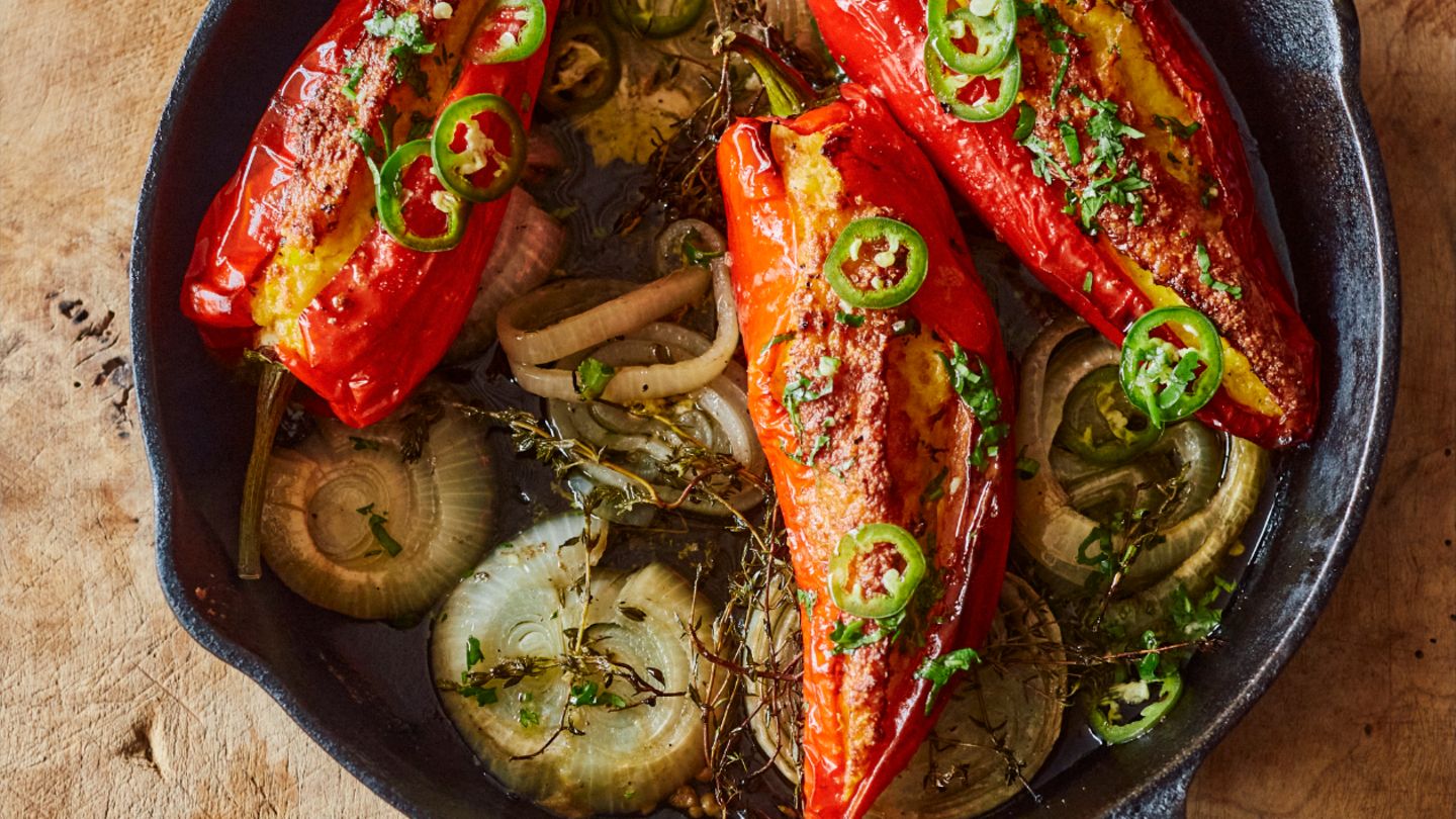 Paprikaschoten mit Maisfüllung und gepickelten Jalapeños      Zutaten:  1 grüne Jalapeño-Chilischote, in feine Ringe geschnitten (15 g), 2 EL Apfelessig, 1 TL Zucker, 250 g TK-Maiskörner, aufgetaut, 100 g Schlagsahne, 50 g Instant-Polenta, 3 Knoblauchzehen, zerdrückt, 1 Ei, 105 ml Olivenöl, 75 g schnittfester Mozzarella, grob gerieben, 75 g gereifter Cheddar, grob gerieben, 4 rote Spitzpaprikaschoten, 2 Zwiebeln, jeweils in 5 Scheiben à 1 cm geschnitten, 5 g Thymianzweige, 10 g Koriandergrün, fein gehackt, Salz und schwarzer Pfeffer      Zubereitung:  1. Den Backofen auf 180 °C (Umluft) vorheizen.  2. Die Chiliringe in einer kleinen Schüssel mit Essig und Zucker verrühren. Beiseitestellen.  3. Den Mais mit Sahne, Polenta, zwei Dritteln des Knoblauchs, dem Ei, 1 EL Öl, ¾ TL Salz und 1 sehr kräftigen Prise Pfeffer im Mixer in wenigen kurzen Intervallen sehr grob pürieren. In eine Schüssel geben und beide Käsesorten unterrühren.  4. Die Paprikaschoten mit einem kleinen scharfen Messer längs einschneiden, ohne die Enden zu durchtrennen; die Stiele intakt lassen. Mit den Fingern die Kerne vorsichtig entfernen. Die Schoten mit der Maismischung füllen.  5. In einer großen gusseisernen Pfanne 1 EL Öl verteilen und mit Zwiebelscheiben und Thymian bedecken; leicht salzen und pfeffern. Die Paprikaschoten mit der Öffnung nach oben auf die Zwiebeln setzen und mit 1 EL Öl beträufeln. Mit etwas Salz und Pfeffer bestreuen, dann 200 ml Wasser in die Pfanne (nicht auf die Paprikaschoten) gießen. 30 Minuten backen, dann die Ofentemperatur auf 200 °C (Umluft) erhöhen und die Schoten weitere 20 Minuten backen, bis alles weich und schön gebräunt ist.  6. Inzwischen die restlichen 4 EL Öl in einer kleinen Schüssel mit Koriandergrün, 1 Msp. Salz und etwas Pfeffer verrühren.  7. Die Paprikaschoten mit dem Koriander-Öl beträufeln, mit den gepickelten Jalapeños bestreuen und warm servieren.