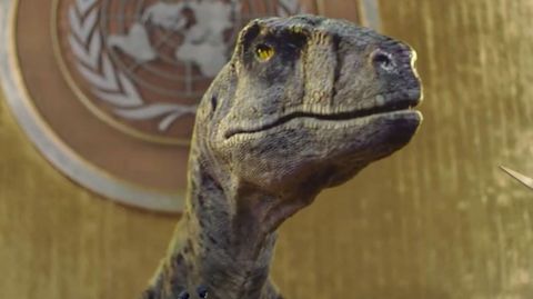 Ein Dinosaurier steht vor dem Rednerpult des UNO-Parlamentes.