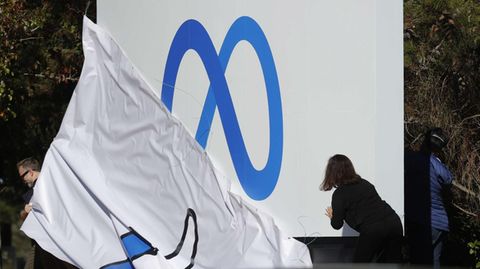 Eine Mitarbeiterin enthüllt das neue Logo gegenüber des Facebook-Hauptquartier
